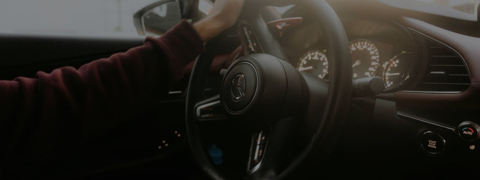 Imagem de uma pessoa dentro do carro com a mão no volante.